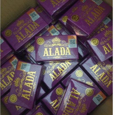 Stack of purple 'ALADA' product boxes with gold text representing Alada Whitening Soap