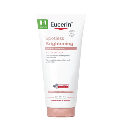 A tube of Eucerin Spotless Brightening Body Lotion on a plain white background. The tube is white with pink and green text and graphics, and has a pale pink cap.