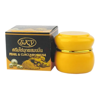 Yellow cream jar with gold lid and black box labeled 'SKY Pearl & CURCUMIN CREAM' on a white background